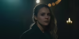 a woman in black jacket standing by some candles