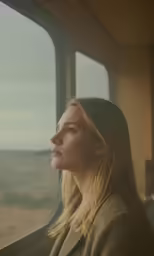a beautiful blonde woman sitting in a passenger train