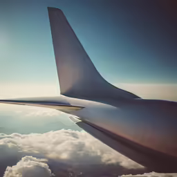 the wing of a passenger jet flying over some clouds