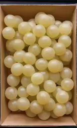 a box filled with white grapes on a table
