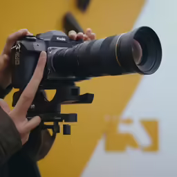 a person holding up a camera lens with a finger on it