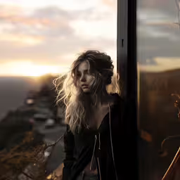 a woman standing on a ledge in front of a glass window,a girl leaning against a glass wall with her headphones in hand