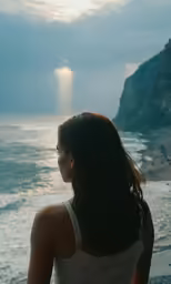a woman standing by the ocean looking at the water