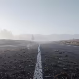 a road is surrounded by mountains and clouds