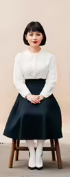 a woman wearing white is sitting on a stool
