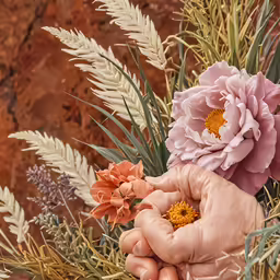 someone holding a flower and standing near a mountain