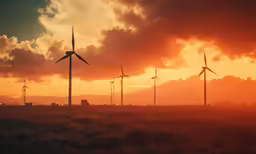 a number of windmills in a field with sunset in the background