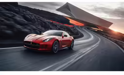 the front view of a red sports car on a winding road