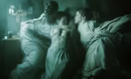 three people sleep next to each other under a blanket