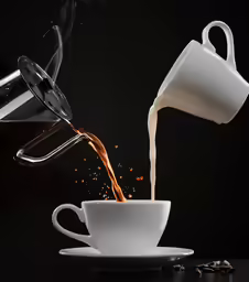 a coffee is pouring from a metal strainer into a cup