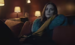 a woman is sitting on the couch with a phone