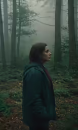 a woman standing in the middle of a forest