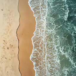 view from above of two waves breaking on a sandy beach