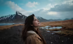 the woman stands in front of snowy mountains