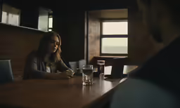 people are sitting at the bar, one with a glass and another with water
