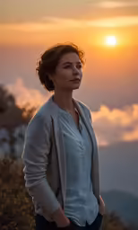 woman standing on top of a hill with the sun setting