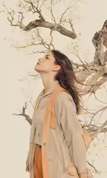 a woman looks up as she walks under the branches