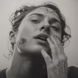 a woman with tattoos holds her hand on her lip