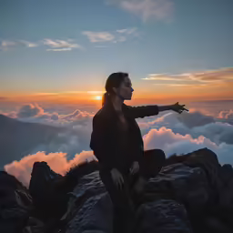 a person sitting on a mountain while looking up at the clouds