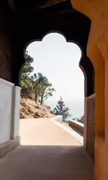 an arched walkway at the edge of a rocky hill