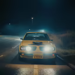 a yellow car parked by itself on a dark road