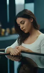 a woman is sitting at a table and looking down on her hands