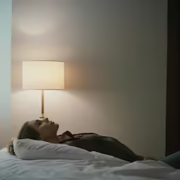 woman lying in bed and sleeping underneath lamp