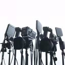 a row of camera setup stands with two microphones on top