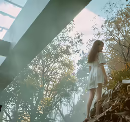 a girl standing near an underpass with trees on either side