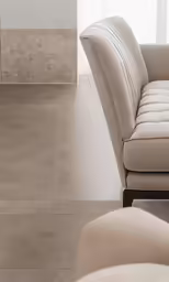 a living room with a beige leather couch and white walls
