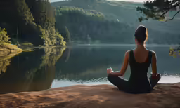 a woman in black dress sitting on beach and meditating