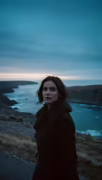 a woman is standing near the ocean