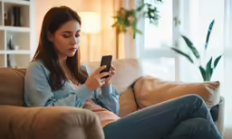 woman sitting on couch with smartphone in her hand