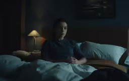 a person is sitting in bed with their hands folded