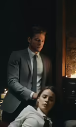 a man in a grey suit and woman wearing a white shirt and tie