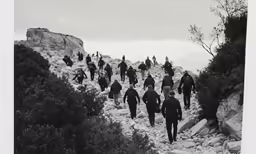 black and white image of men in black suits climbing
