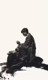 a man sitting on the ground looking at a cell phone