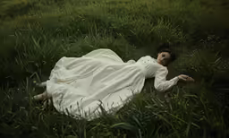 a woman is sleeping in tall grass