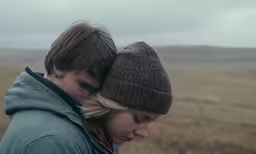 a couple is in a field with the rain falling on their hats