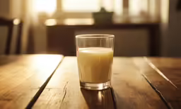 a glass of milk sits on a table