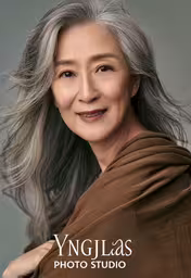 the face and shoulders of an older asian woman in a studio,an elderly woman with long white hair posing for a portrait