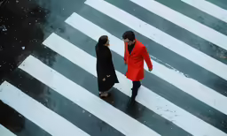 two women walking across a crosswalk in the rain