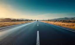 a lone figure stands in the middle of an empty road