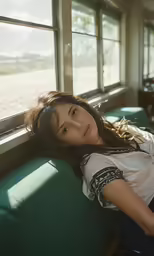 young girl looking out window while resting on the green sofa