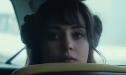 a woman drives in the back of a car