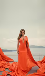 the woman is posing on the dock in an orange dress
