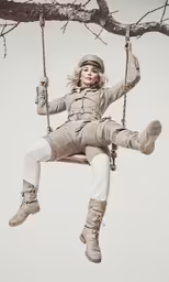 a woman with boots on is sitting on the swings