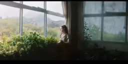 a woman standing at a window in front of plants
