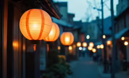 several large lanterns lit in the street next to buildings