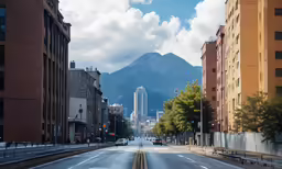 cars drive down a street lined with tall buildings